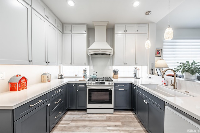 kitchen featuring pendant lighting, premium range hood, white dishwasher, sink, and stainless steel gas stove