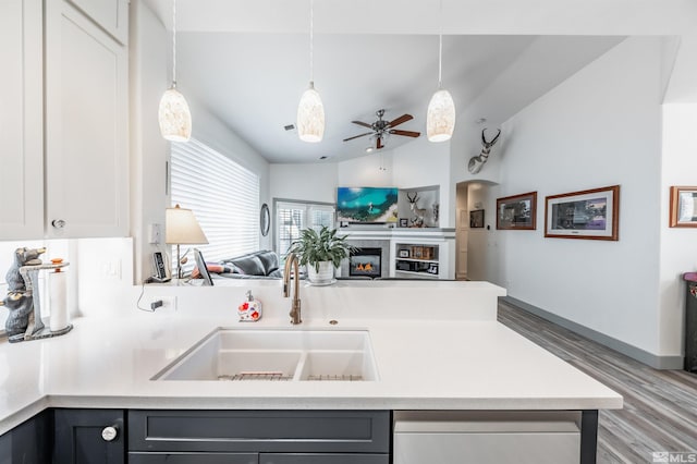 kitchen featuring vaulted ceiling, ceiling fan, sink, white cabinetry, and hanging light fixtures