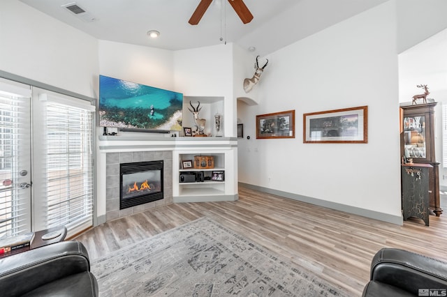 living room with a fireplace, vaulted ceiling, light hardwood / wood-style flooring, and ceiling fan