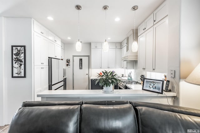 kitchen with white cabinets, decorative light fixtures, white fridge, and kitchen peninsula