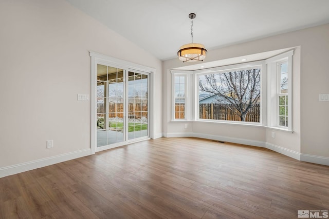 unfurnished dining area featuring lofted ceiling and light hardwood / wood-style flooring