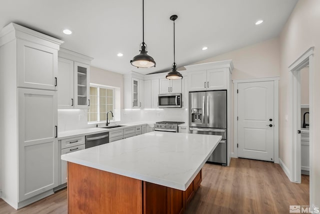 kitchen featuring white cabinetry, a center island, sink, hanging light fixtures, and stainless steel appliances