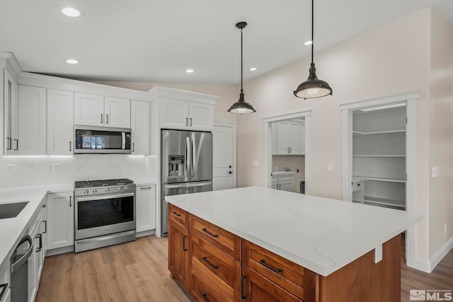 kitchen with decorative backsplash, stainless steel appliances, a center island, white cabinetry, and hanging light fixtures