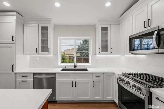 kitchen with stainless steel appliances, white cabinetry, and sink