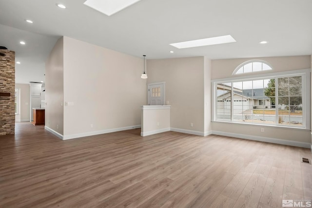 unfurnished living room with lofted ceiling with skylight and hardwood / wood-style flooring