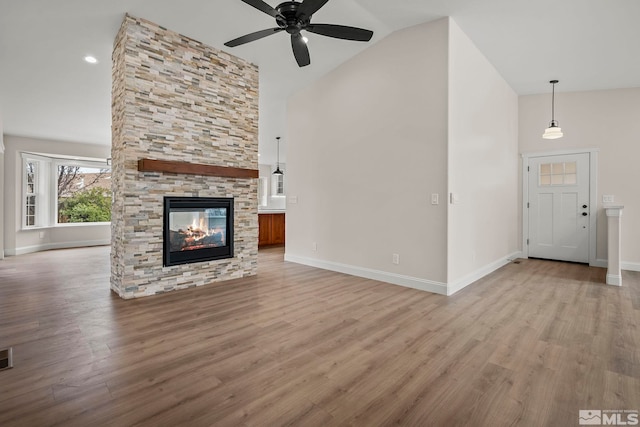 unfurnished living room featuring a fireplace, light hardwood / wood-style flooring, vaulted ceiling, and ceiling fan