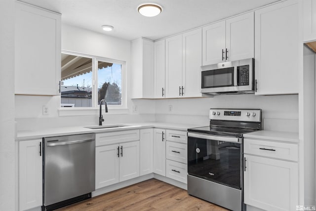 kitchen with white cabinetry, sink, stainless steel appliances, and light hardwood / wood-style flooring