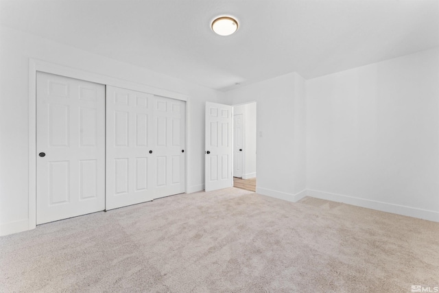 unfurnished bedroom with a closet and light colored carpet