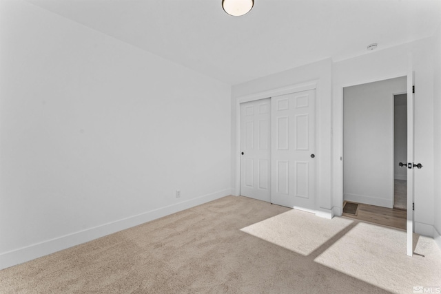 unfurnished bedroom featuring light colored carpet and a closet