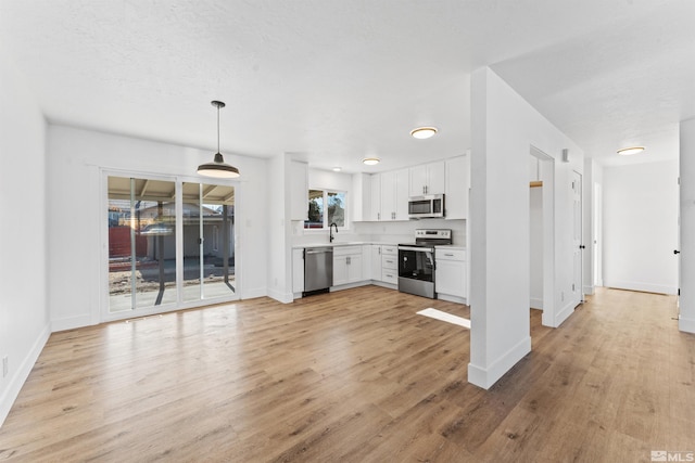 kitchen with white cabinetry, sink, stainless steel appliances, light hardwood / wood-style flooring, and pendant lighting