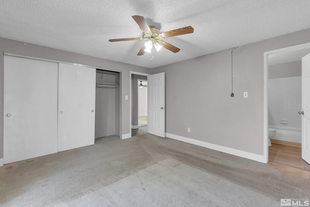 unfurnished bedroom with light carpet, a textured ceiling, ensuite bath, and ceiling fan