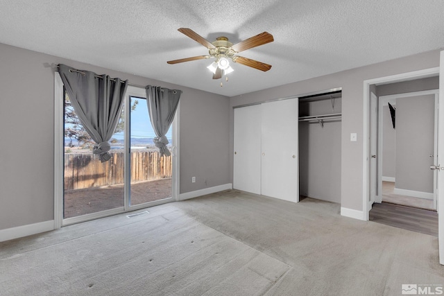 unfurnished bedroom featuring access to exterior, ceiling fan, a textured ceiling, light carpet, and a closet