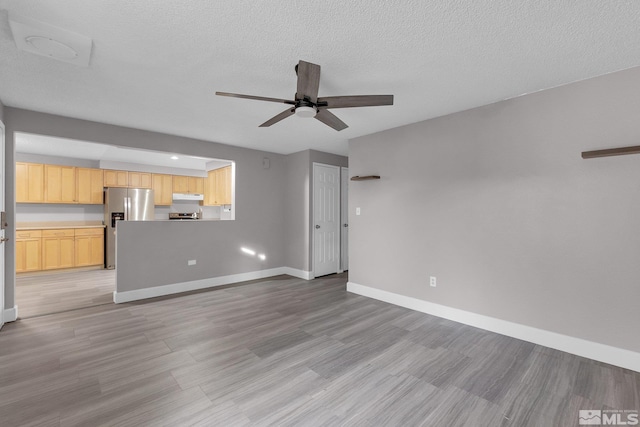 unfurnished living room featuring ceiling fan, light hardwood / wood-style floors, and a textured ceiling