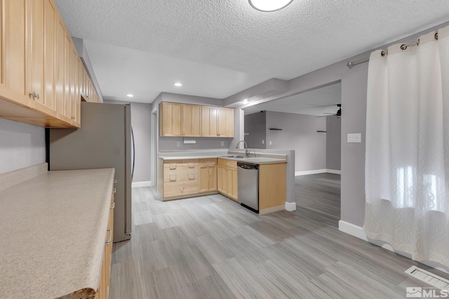 kitchen featuring sink, stainless steel dishwasher, light hardwood / wood-style floors, a textured ceiling, and light brown cabinetry