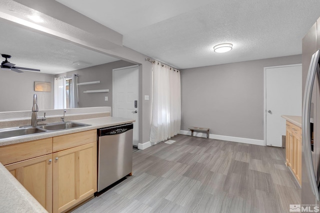 kitchen with appliances with stainless steel finishes, light brown cabinetry, a textured ceiling, ceiling fan, and sink