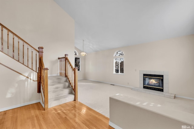 unfurnished living room featuring a tile fireplace, light hardwood / wood-style flooring, and lofted ceiling