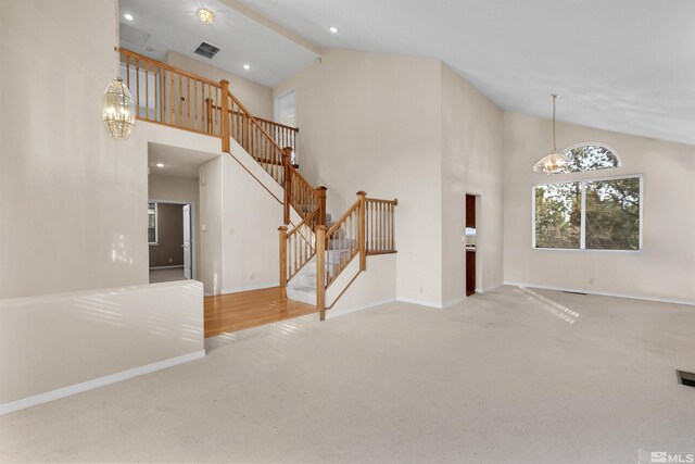 unfurnished living room with beam ceiling, high vaulted ceiling, light colored carpet, and an inviting chandelier