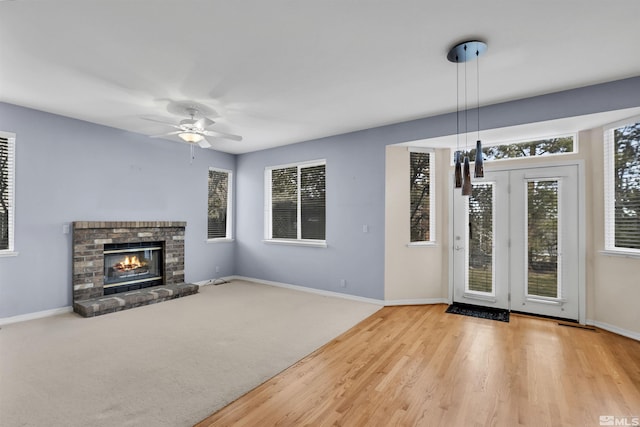 unfurnished living room with ceiling fan, a fireplace, and light colored carpet