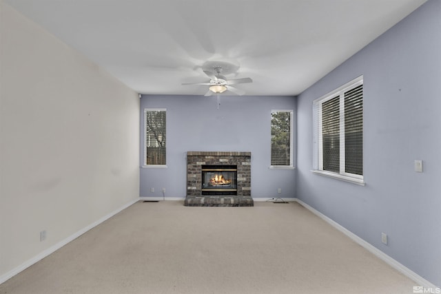 unfurnished living room with ceiling fan, light colored carpet, and a brick fireplace