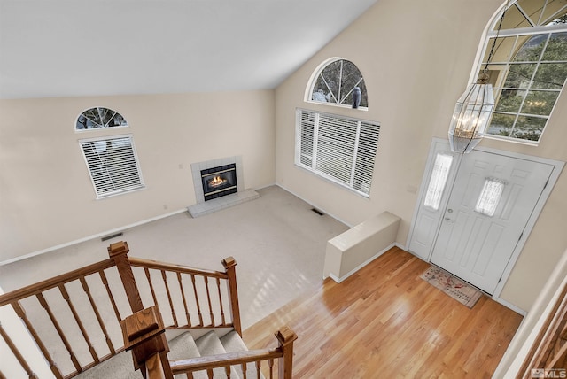 entrance foyer with a fireplace, wood-type flooring, a chandelier, and a healthy amount of sunlight