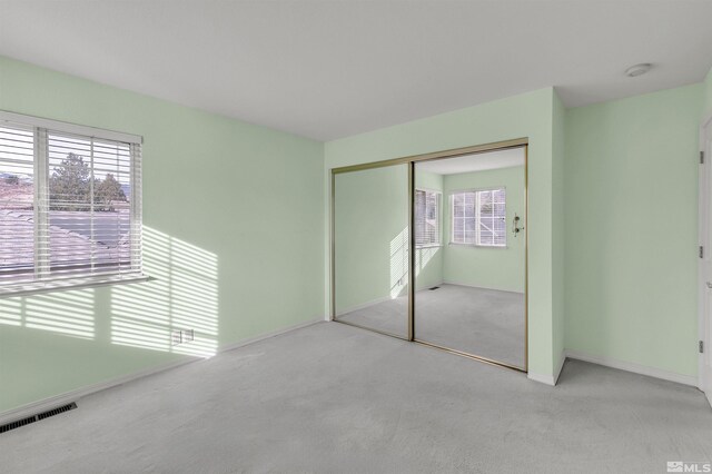 unfurnished bedroom with light colored carpet and a closet