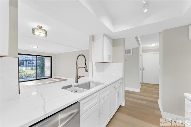 kitchen featuring sink, light wood-type flooring, tasteful backsplash, light stone counters, and white cabinetry