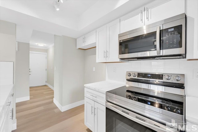 kitchen featuring light stone countertops, light hardwood / wood-style flooring, white cabinets, and stainless steel appliances