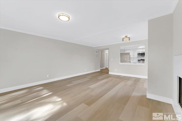 unfurnished living room featuring sink, a fireplace, and light wood-type flooring