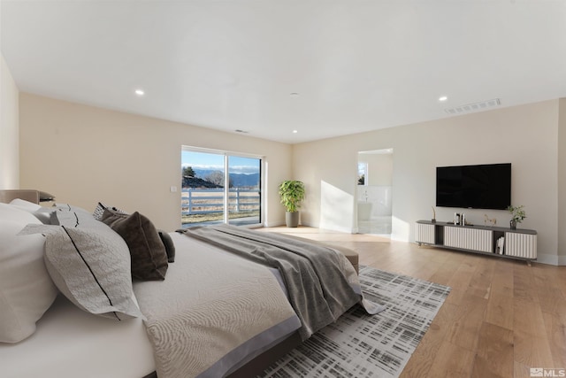 bedroom featuring access to exterior, ensuite bathroom, and light hardwood / wood-style flooring