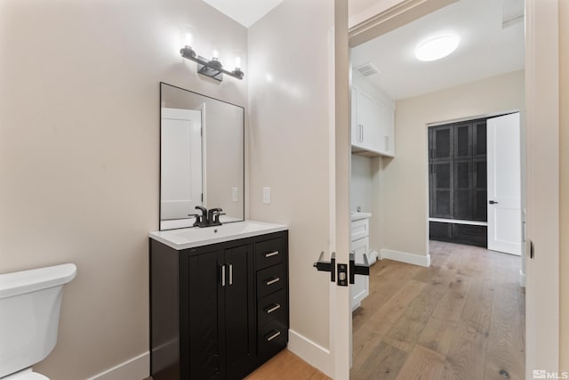 bathroom with hardwood / wood-style floors, vanity, and toilet