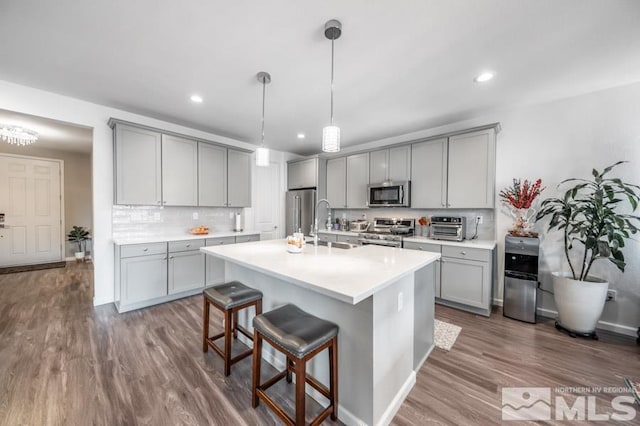 kitchen with gray cabinetry, a kitchen island with sink, and appliances with stainless steel finishes