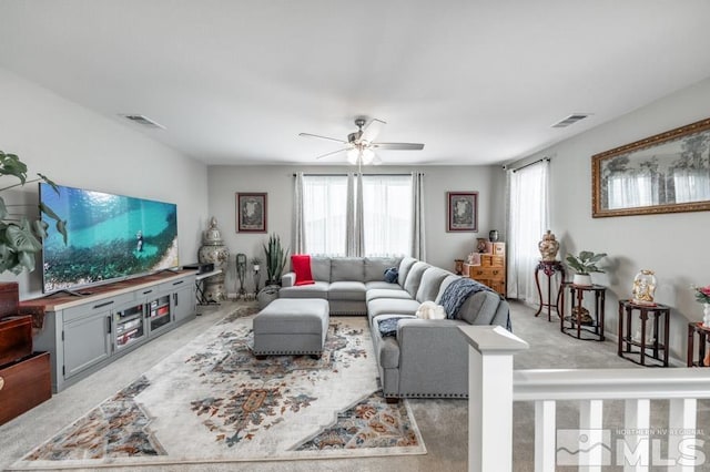 living room with a wealth of natural light, ceiling fan, and light carpet