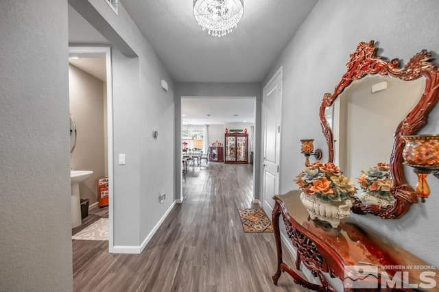 hallway with wood-type flooring and a notable chandelier