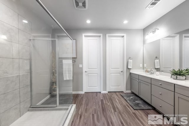 bathroom with hardwood / wood-style floors, vanity, and a shower with shower door