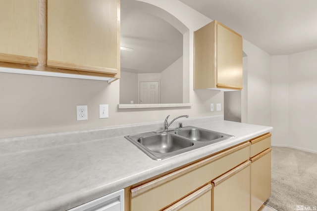 kitchen featuring light brown cabinetry, sink, and light carpet