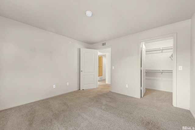 unfurnished bedroom with light colored carpet, a spacious closet, and a closet