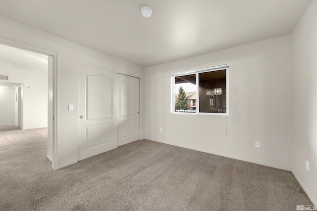 unfurnished bedroom with light colored carpet and a closet