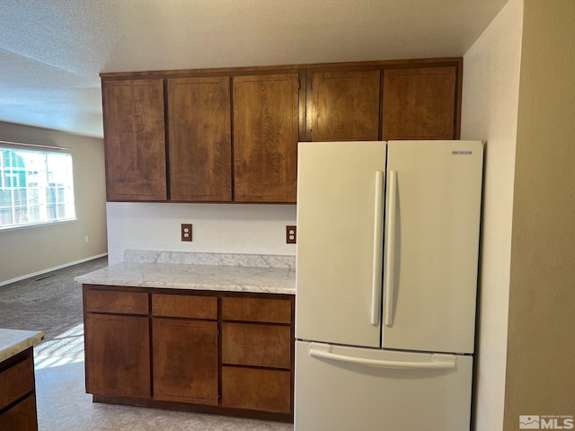 kitchen featuring a textured ceiling, white fridge, and light colored carpet