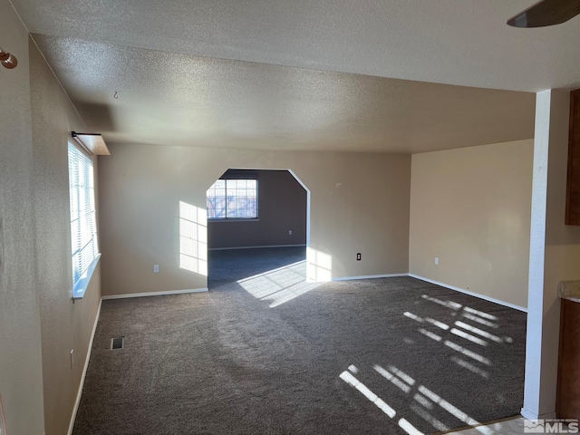 interior space featuring a textured ceiling and dark colored carpet