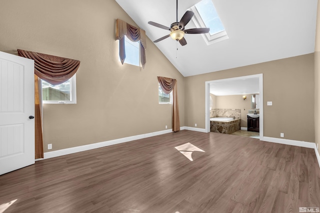 unfurnished living room with a skylight, ceiling fan, hardwood / wood-style floors, and high vaulted ceiling