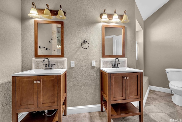 bathroom featuring vanity, vaulted ceiling, and toilet