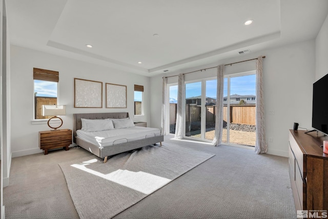 bedroom featuring access to outside, a tray ceiling, and light colored carpet