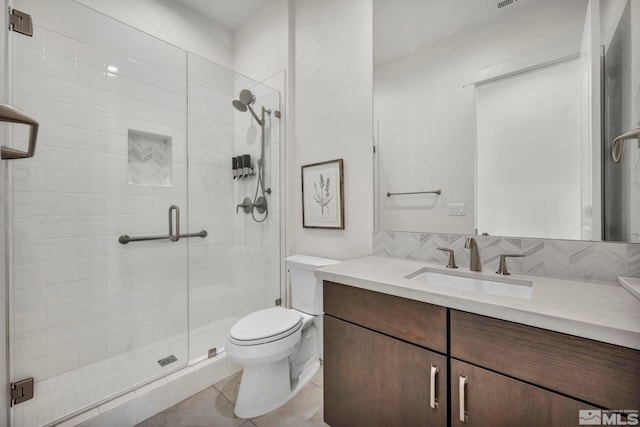 bathroom with backsplash, vanity, a shower with door, tile patterned flooring, and toilet