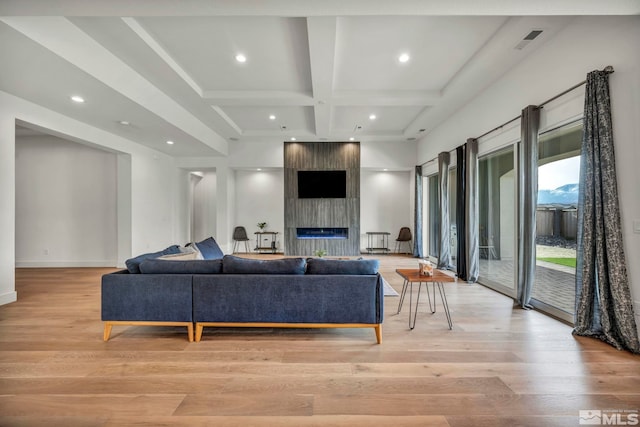 living room with beamed ceiling, a large fireplace, light hardwood / wood-style flooring, and coffered ceiling