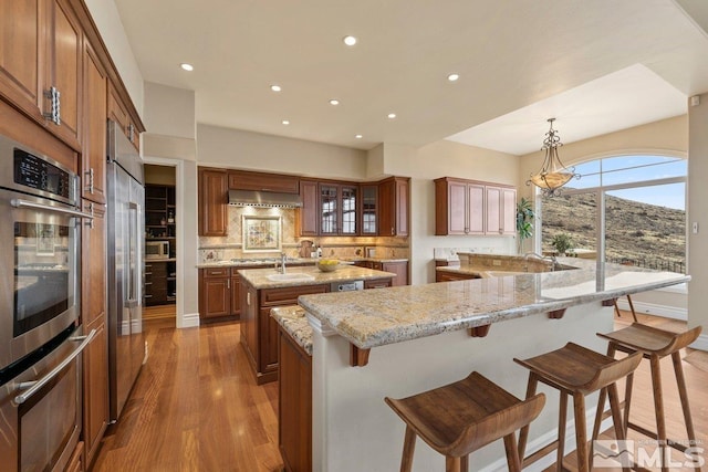 kitchen with tasteful backsplash, light stone counters, hanging light fixtures, and a spacious island