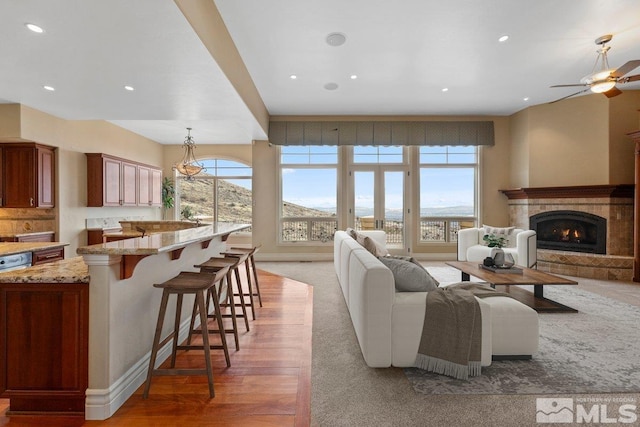 living room with a tile fireplace, a mountain view, and plenty of natural light