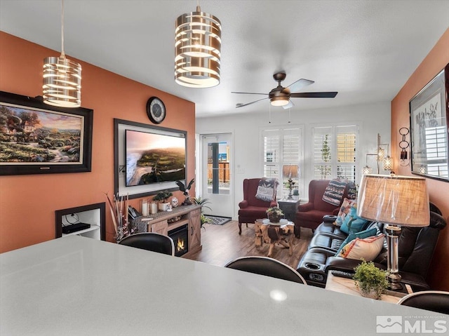 living room with ceiling fan with notable chandelier and hardwood / wood-style flooring