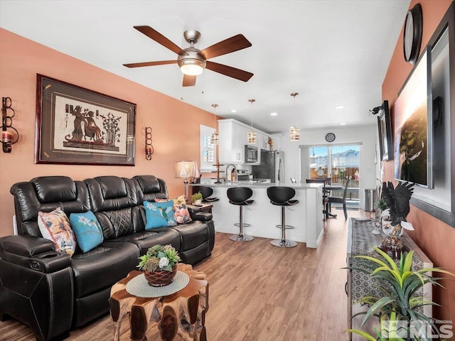 living room with ceiling fan, light hardwood / wood-style flooring, and sink