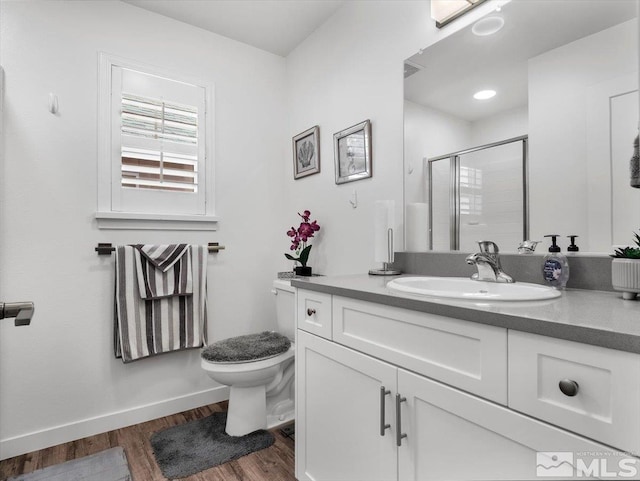 bathroom with hardwood / wood-style flooring, vanity, toilet, and walk in shower