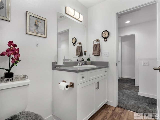 bathroom featuring wood-type flooring, vanity, and toilet